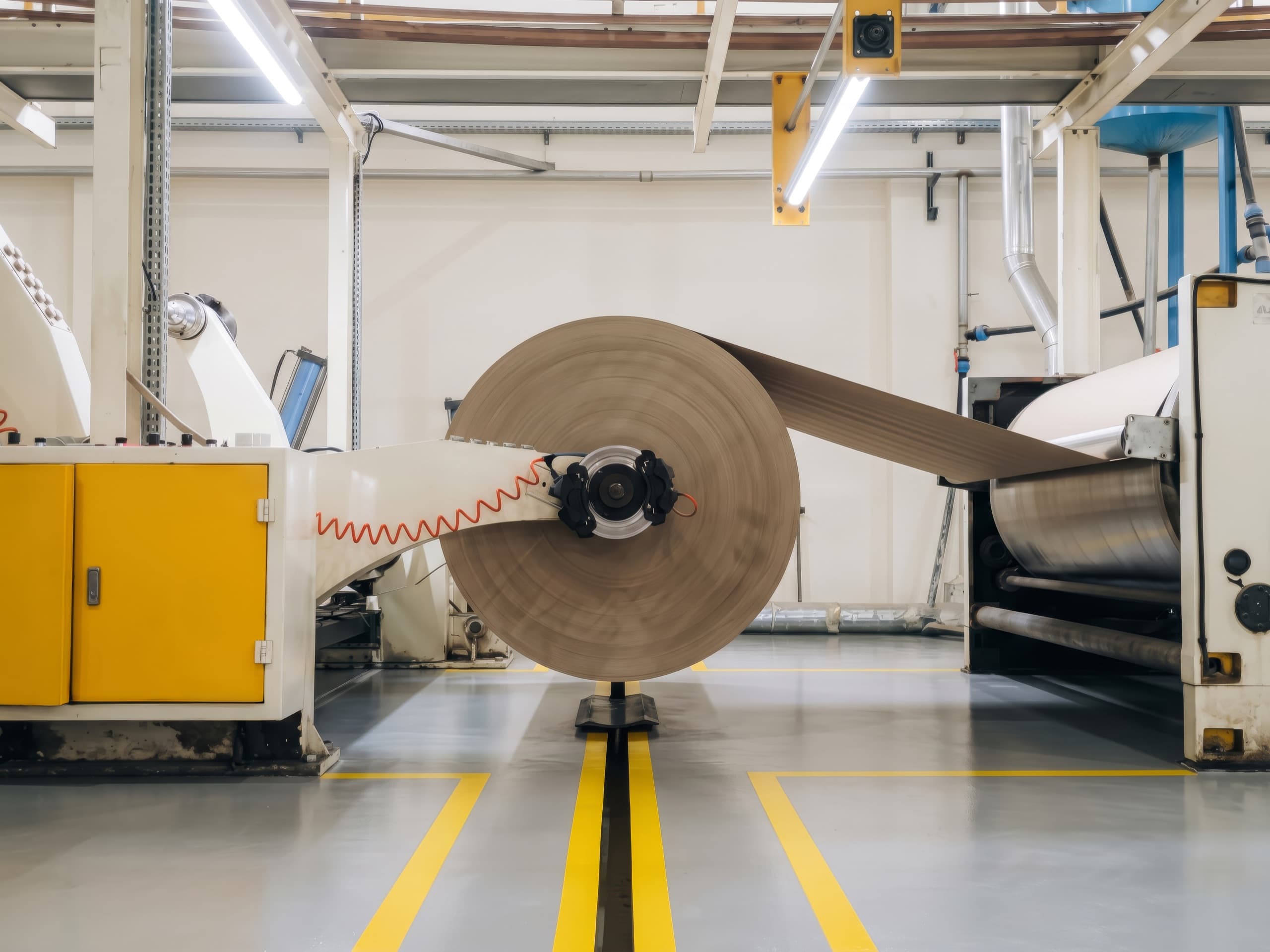 A roll of kraft paper unwinding on a production machine